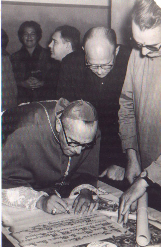 Monseñor Aguirre firmando el Acta de Fundación de nuestro Colegio. Detrás el Padre Pooli